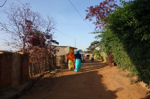 Two women with headscarves are walking through an unpaved road in the Muslim quarter Nyamirambo.